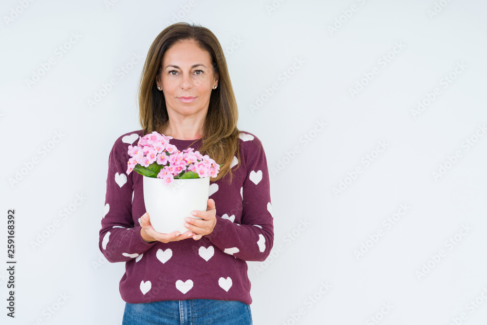 Middle age woman holding flowers pot plant over isolated background with a confident expression on smart face thinking serious Middle age woman holding flowers pot plant over isolated background with a confident expression on smart face thinking serious
