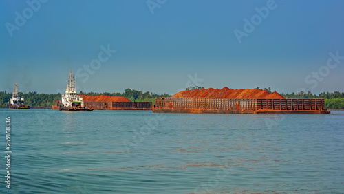 Tug boats with a large cargo barges transporting bauxite ore in Kamsar, Guinea.