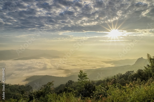 Mountain view morning of the hills around with sea of mist and soft yellow sun light with cloudy sky background, sunrise at Doi Samur Dao, Sri Nan National Park, Nan, Thailand.