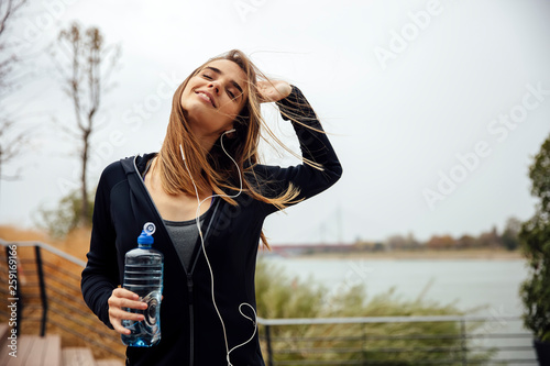 Young beautiful women resting and drinking water after doing exercises