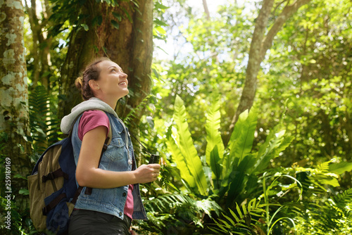 Hiker watching through binoculars wild birds in the tropical jungle. photo