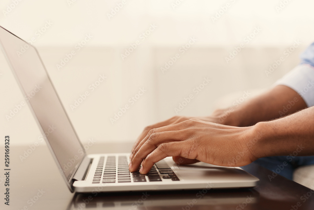 Black man blogger typing on laptop at home
