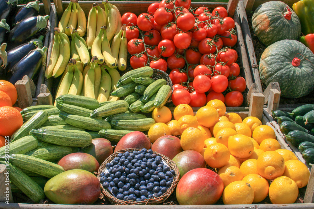 Beautiful composition of various fresh and ripe biological vegetables and fruits in wooden boxes in a market