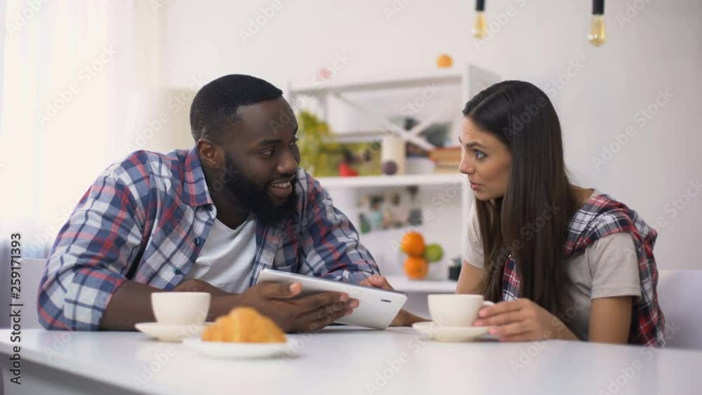 Mixed-race family scrolling on tablet pc during breakfast, shopping online Mixed-race family scrolling on tablet pc during breakfast, shopping online