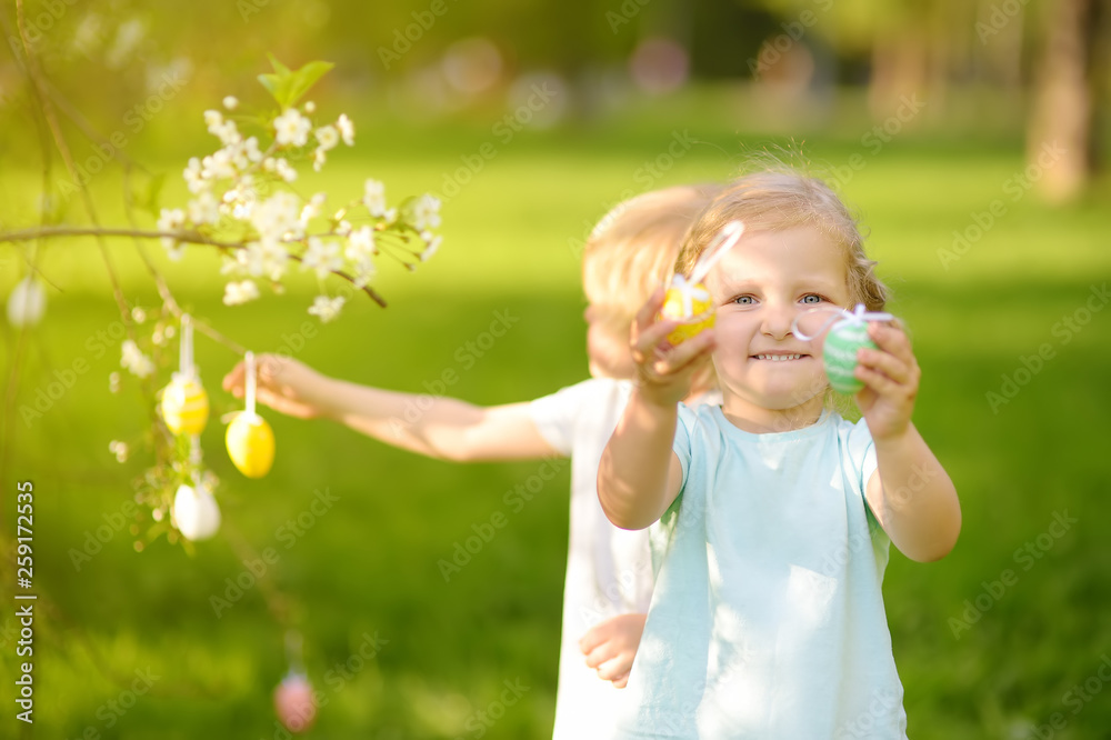 Charming little children hunts for painted eggs in spring park on Easter day. Charming little children hunts for painted eggs in spring park on Easter day.
