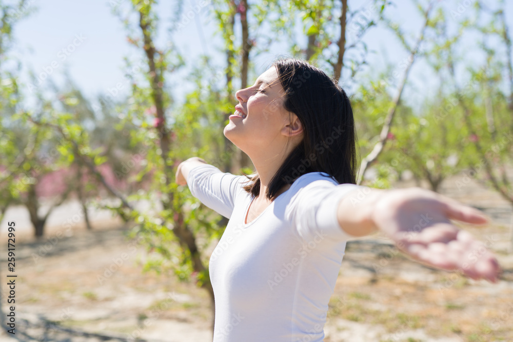 Beautiful young woman smiling cheerful with open arms and eyes closed relaxing and enjoying sunbathe in a sunny day of spring