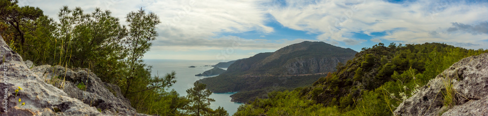 Coastal mountainside surrounded by turquoise water in a steep valley, Oludeniz, Turkey panoramic