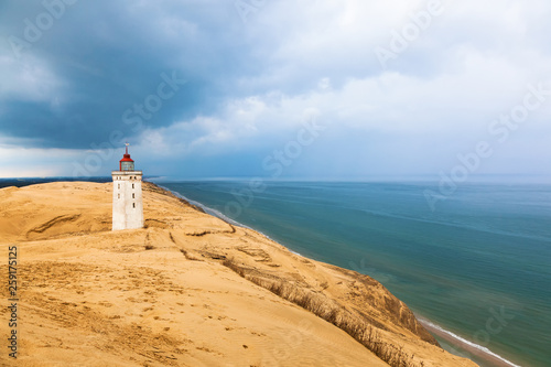 Lighthouse on Rabjerg mile on the Danish coast with storm clouds in the sky