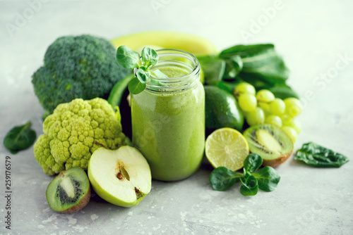 Foto Glass jar mugs with green health smoothie, kale leaves, lime, apple, kiwi, grapes, banana, avocado, lettuce