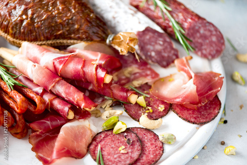 Fototapeta Naklejka Na Ścianę i Meble -  Cold smoked meat plate. Traditional italian antipasto, cutting board with salami, prosciutto, ham, pork chops, olives on grey background. Top view, copy space, flat lay
