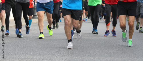 legs of many runners at footrace in  the city