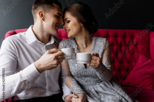 The bride and groom with coffee cups hug each other