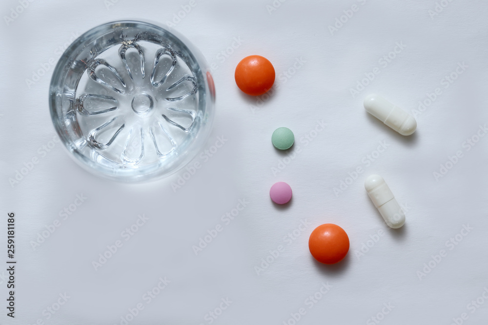 Bright colored tablets, pills, capsules on a glass table.