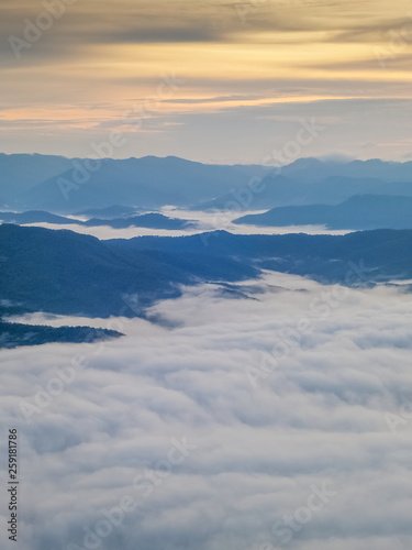 Mountain view morning of the hills around with sea of mist and soft yellow sun light in the sky background, sunrise at Doi Samur Dao, Sri Nan National Park, Nan, Thailand.