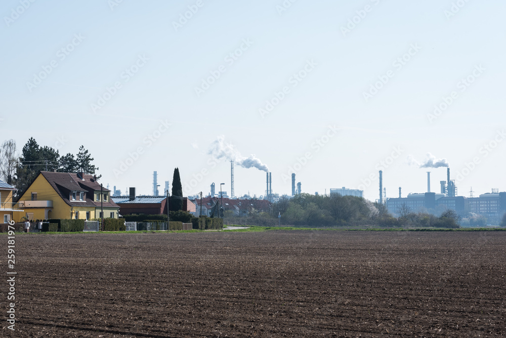 industrial plant with chimneys and smoke and a field in front industrial plant with chimneys and smoke and a field in front