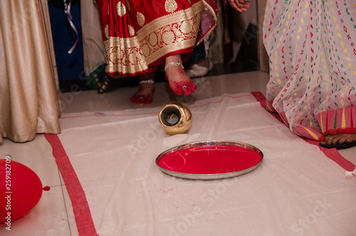 Indian wedding rituals, Gruha Pravesh / Gruhapravesh / Griha Pravesh, closeup picture of right feet of a Newly married Indian Hindu bride dipping her fit in a plate filled with liquid kumkum then step photo