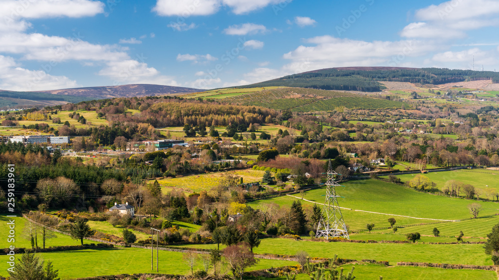 Irish countryside landscape as seen from above, with green meadows and forest covered hills on a sunny spring morning. View from the top of Barnaslingan Hill, Co. Dublin, Ireland.