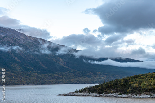 Tranquil scenic mountain and sea landscape in Alaska with low clouds hovering