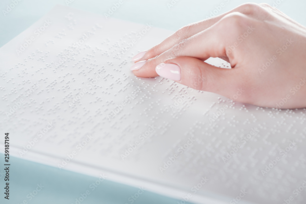 close up view of young woman reading braille text on white paper