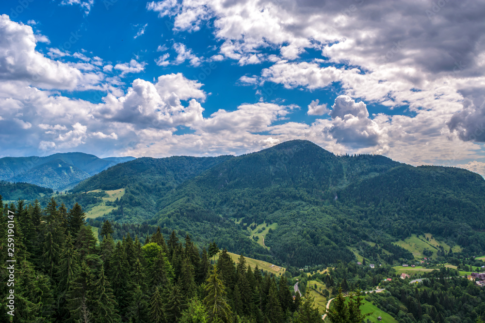 Beautiful mountain scenery with clouds, forests and blue sky in Transylvania, Romania, Eastern Europe. Remote place, vacation, relaxing, fresh air.