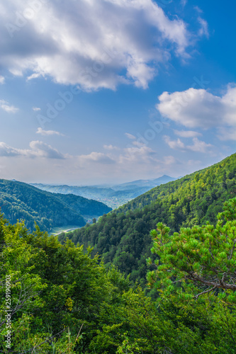 View of forested valley with blue sky and clouds in Arges county ,Romania, East Europe. Untouched virgin woods in Carpathian Mountains.