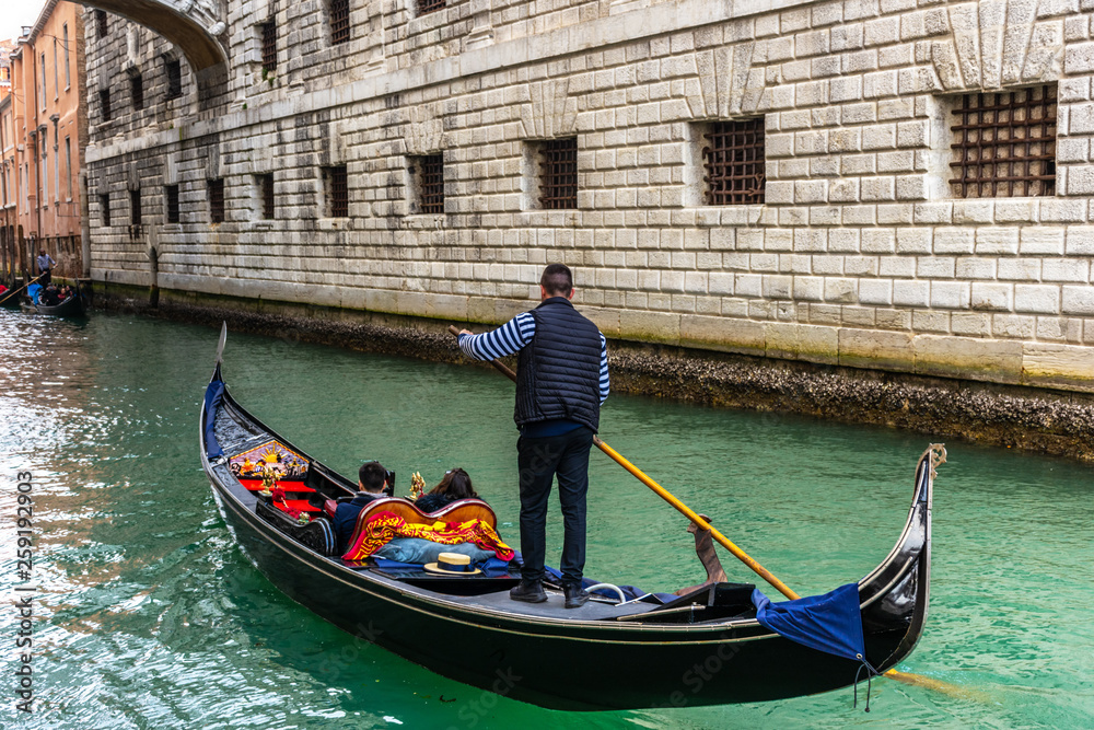 Traditional canal street with gondolier in Venice, Italy