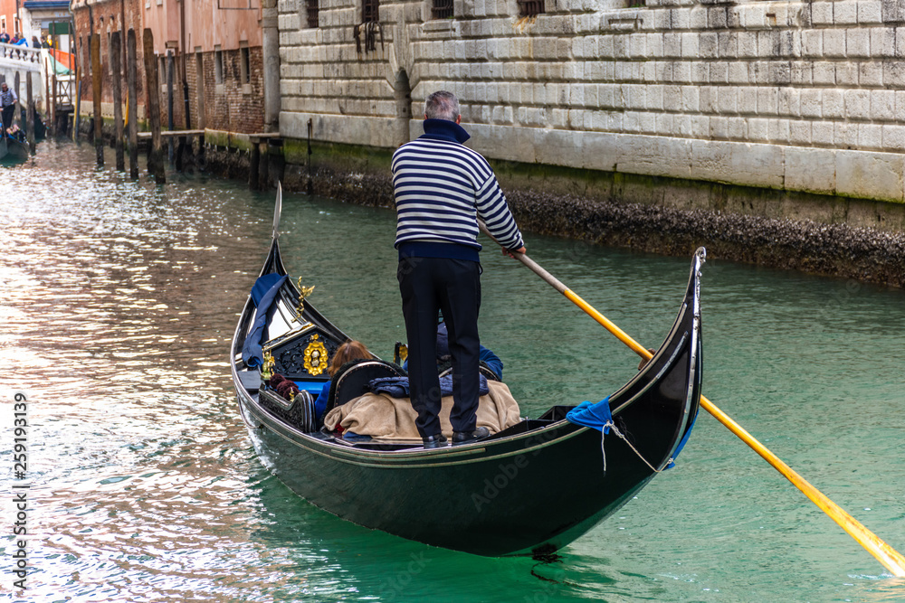 Traditional canal street with gondolier in Venice, Italy