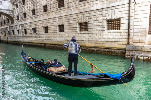 Traditional canal street with gondolier in Venice, Italy