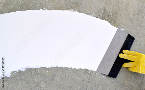 Hand with a spatula, the process of applying a layer of putty. Renovation of apartments. Repair the walls. Free space for advertising, text.