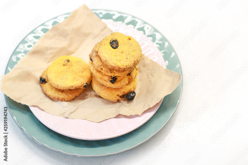 Cookies with raisins on a pink plate. Packing cookies in Kraft paper. Cookies with raisins on a pink plate. Packing cookies in Kraft paper.