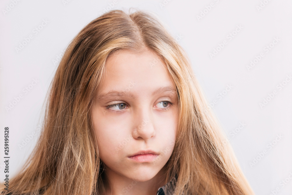 Sad teenage girl on a light background looks to the side and hopes that everything in her will be good Sad teenage girl on a light background looks to the side and hopes that everything in her will be good