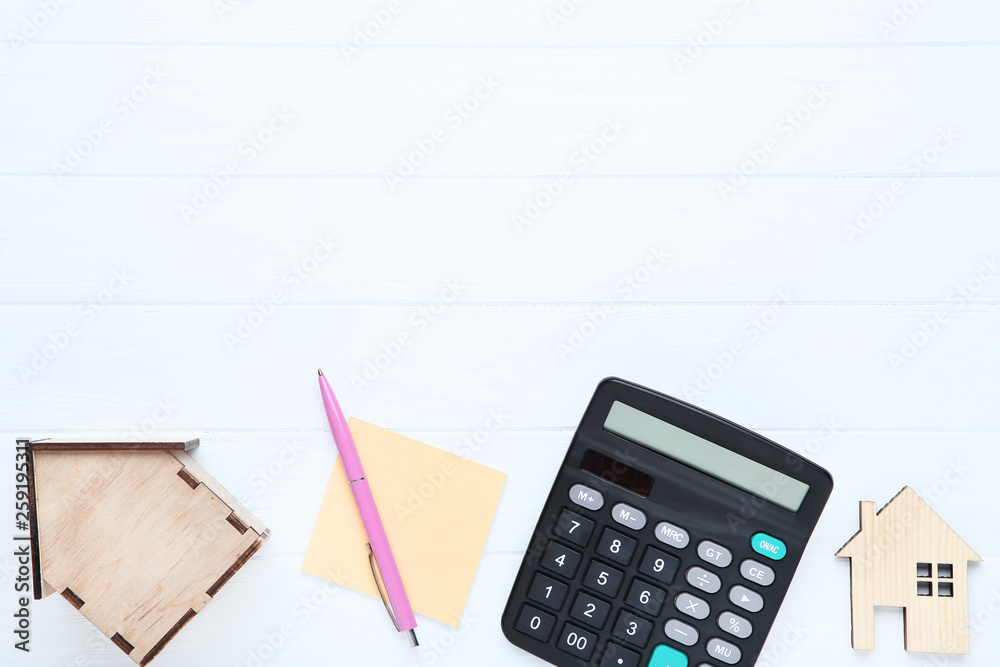 House models with calculator and pen on wooden table House models with calculator and pen on wooden table