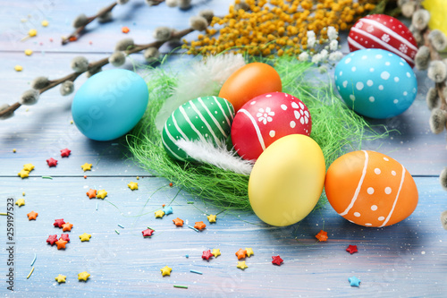 Colorful easter eggs with feathers and sprinkles on blue wooden table