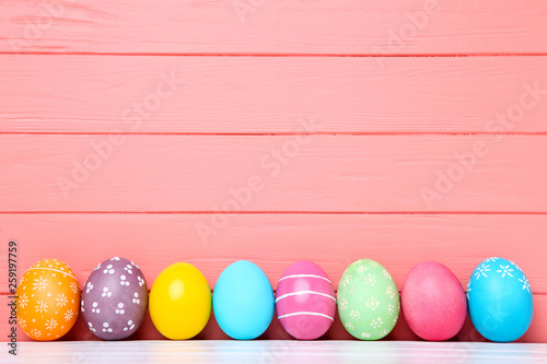 Colorful easter eggs on coral wooden background