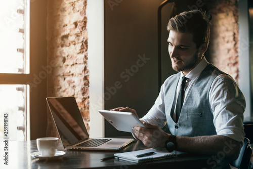 Young handsome student typing on his notebook his diploma. Student discussing on the phone universities's timetable. Education online. Work on freelance. Software development.