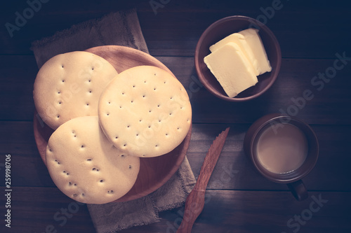 Traditional Chilean Hallulla bread rolls on wooden plate with butter and coffee with milk on the side, photographed overhead on dark wood with natural light (Digitally Altered: Toned Image) photo