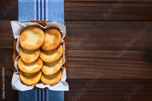 Traditional Chilean Sopaipilla fried pastries made of a bread-like leavened dough served in a basket, photographed overhead on dark wood with natural light photo