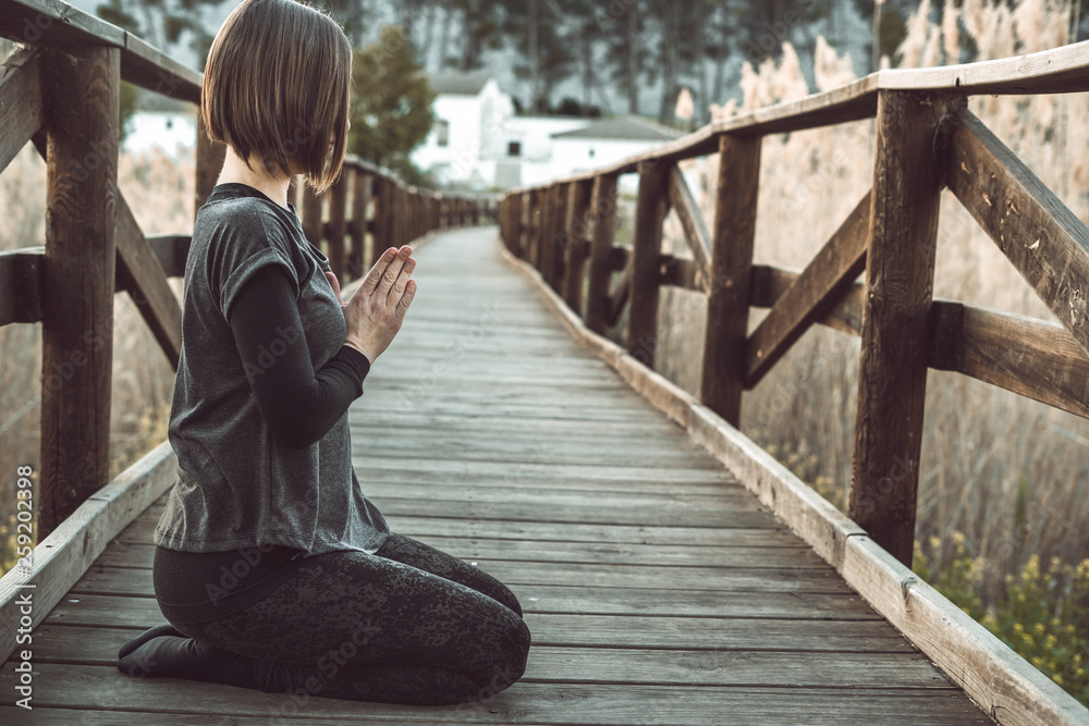 Girl meditating and practicing yoga in nature. Concept of wellness and relaxation Girl meditating and practicing yoga in nature. Concept of wellness and relaxation