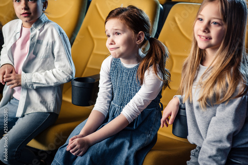 three cute children sitting in cinema and watching movie