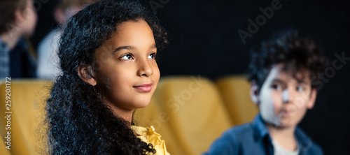 panoramic shot of african american child watching movie together with mixed race friend