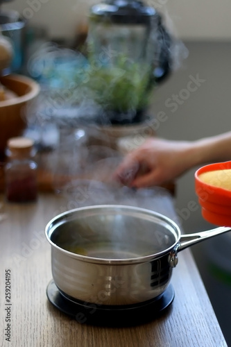 Pan with boiling water and olive oil, for cooking polenta. Selective focus.