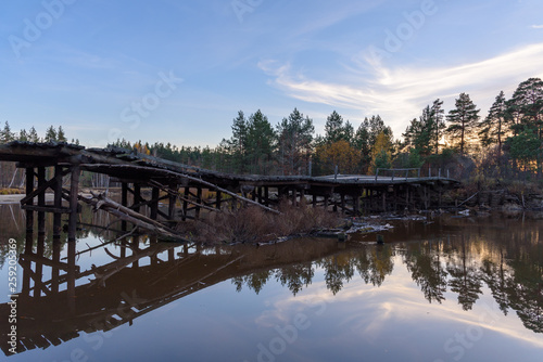Old wooden bridge over the river in the forest