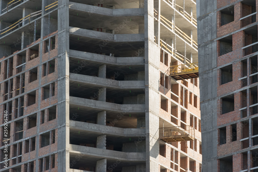 wall with window openings in a multi-storey high-rise residential building under construction from concrete and brick wall with window openings in a multi-storey high-rise residential building under construction from concrete and brick