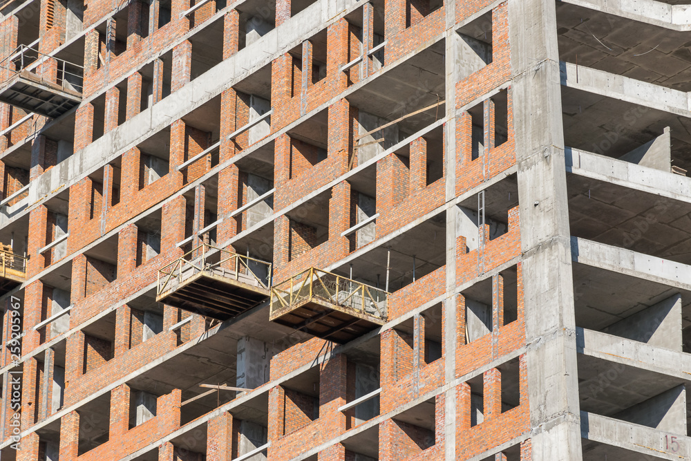 wall with window openings in a multi-storey high-rise residential building under construction from concrete and brick wall with window openings in a multi-storey high-rise residential building under construction from concrete and brick