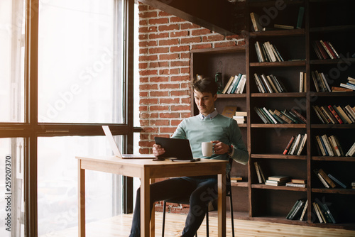 Young handsome student typing on his notebook his diploma. Student discussing on the phone universities's timetable. Education online. Work on freelance. Software development.