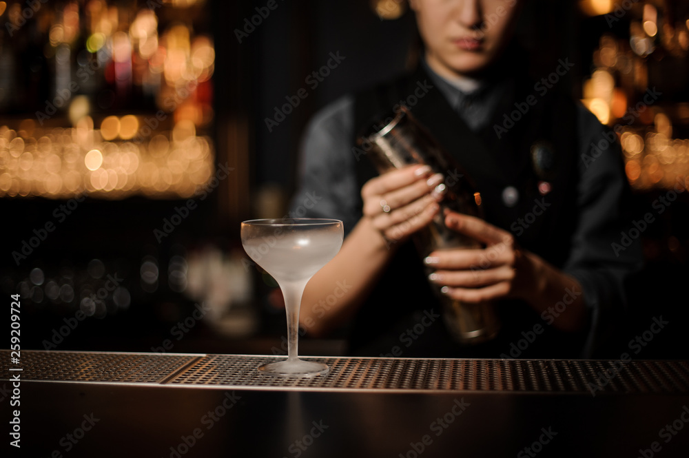 Bartender pours an alcohol cocktail in glass