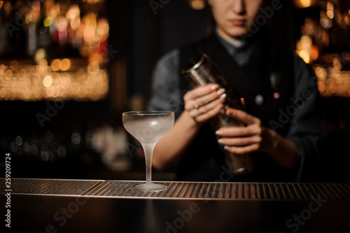 Bartender pours an alcohol cocktail in glass