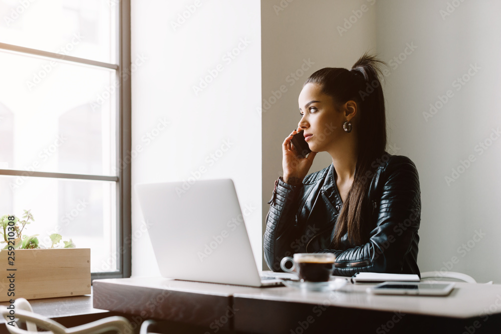 Beautiful girl working out a plan of the project and concept. Girl paints a website design on a laptop. student prints a message on the phone in the messenger. Development. Digital marketing