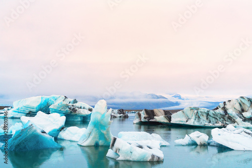 Luminous blue icebergs floating in Jokulsarlon glacial lagoon with background of glacier mountain. South Iceland, VatnajÃ¶kull National Park. Copy space background. Place for text.