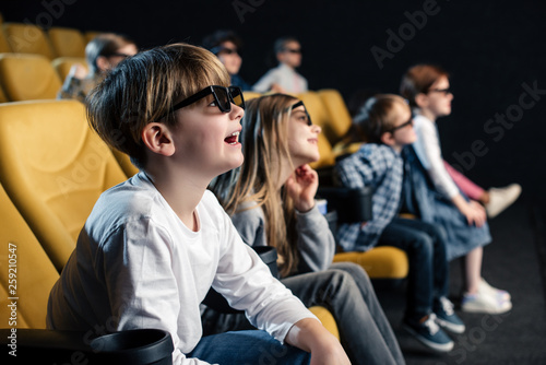 selective focus of cute boy in 3d glasses watching movie in cinema together with friends